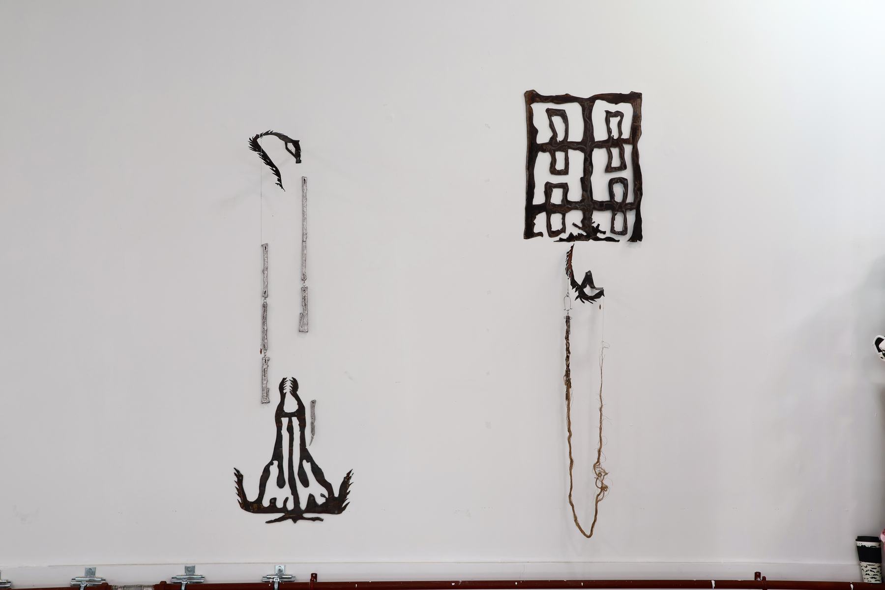 Wall installation with jujube seed forms and hanging elements.
